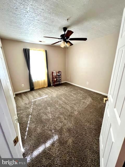 empty room featuring carpet, ceiling fan, and a textured ceiling