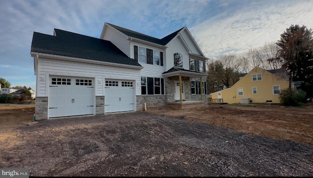 view of front facade featuring stone siding, an attached garage, dirt driveway, and central AC unit