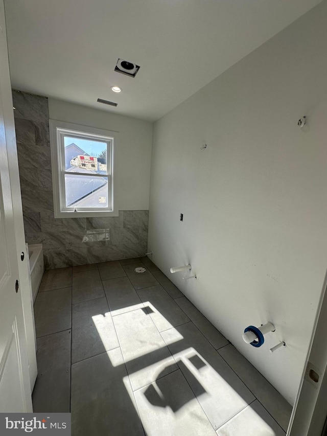 bathroom featuring tile patterned flooring, visible vents, and tile walls