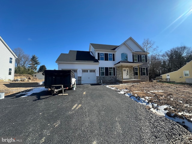 view of front of property with stone siding, an attached garage, and driveway