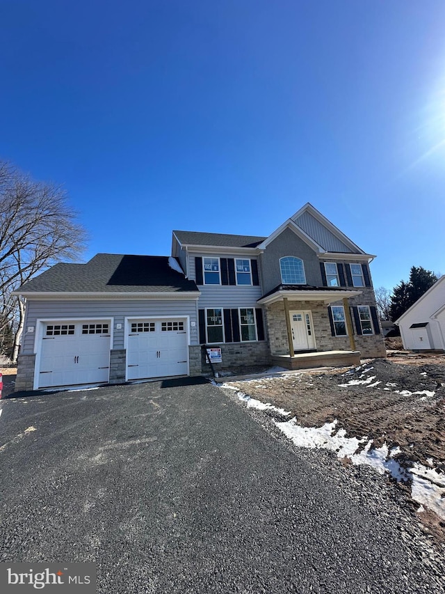 view of front of house with a garage, stone siding, and aphalt driveway