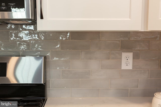 room details featuring white cabinetry and backsplash