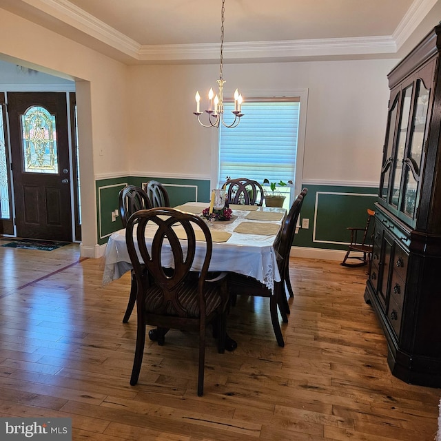 dining space featuring an inviting chandelier, wood-type flooring, and ornamental molding