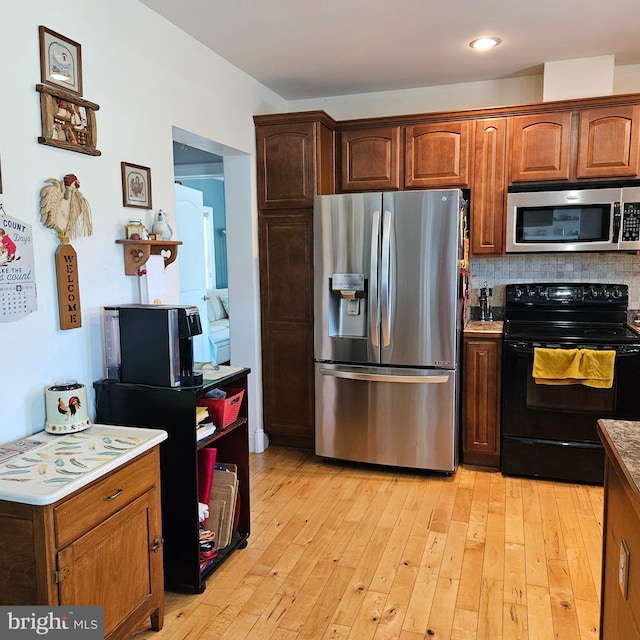 kitchen with backsplash, light hardwood / wood-style flooring, and stainless steel appliances