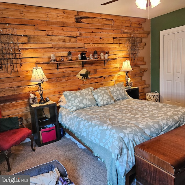 carpeted bedroom with a closet, wooden walls, and ceiling fan