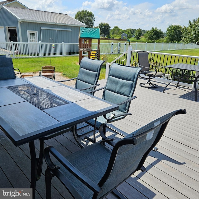 deck featuring a playground, a yard, and an outbuilding