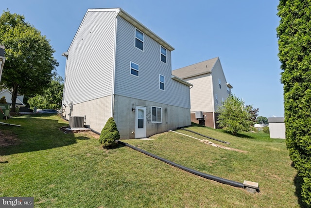 back of property with central AC unit and a lawn