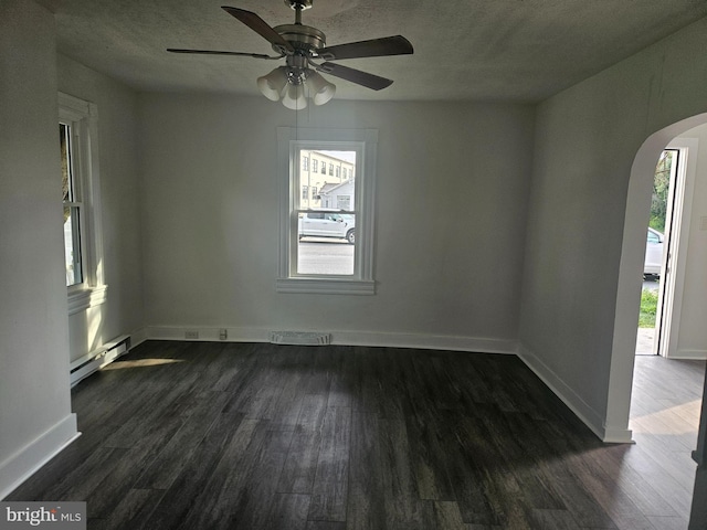 spare room featuring ceiling fan, dark wood-type flooring, a wealth of natural light, and a baseboard radiator