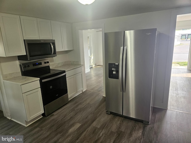 kitchen with stainless steel appliances, dark wood-type flooring, white cabinetry, and light stone counters