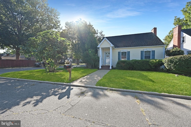 view of front facade featuring a front yard, roof with shingles, and fence