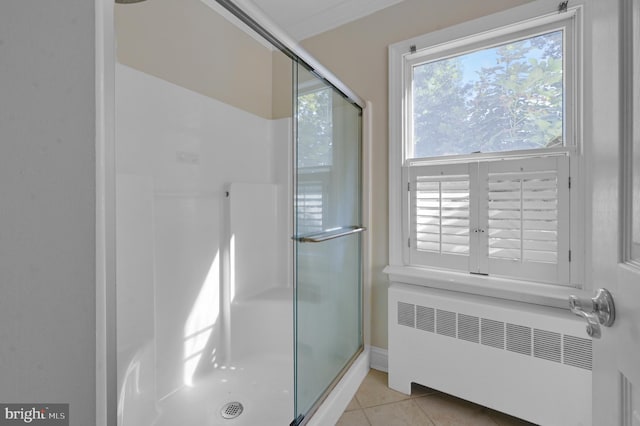 bathroom with radiator heating unit, tile patterned flooring, and a shower with door