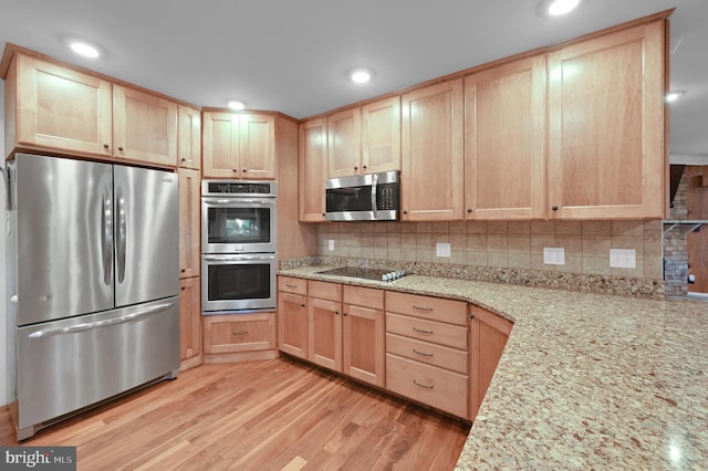 kitchen with stainless steel appliances, light hardwood / wood-style flooring, decorative backsplash, and light stone countertops