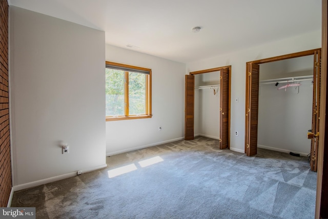 unfurnished bedroom with baseboards, multiple closets, and carpet