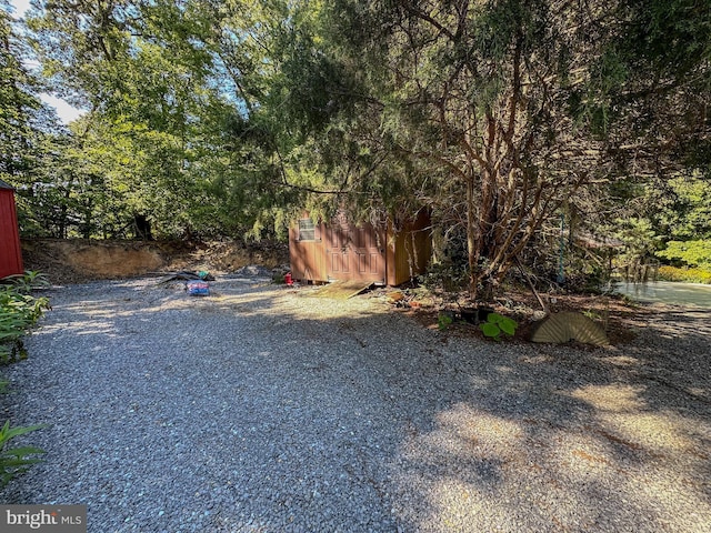 view of yard with gravel driveway, a storage shed, and an outbuilding