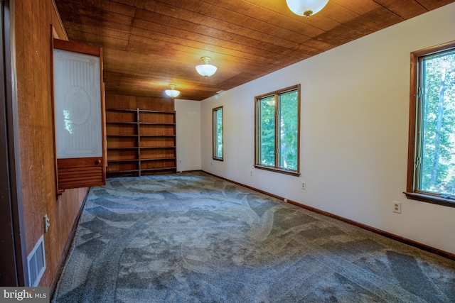 carpeted spare room with visible vents, wooden ceiling, baseboards, and built in features