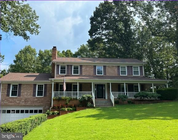 colonial house featuring a garage, a front yard, and a porch