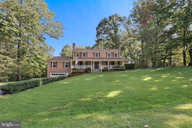 colonial house featuring a garage, covered porch, and a front lawn