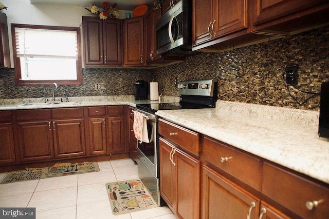 kitchen featuring backsplash, sink, appliances with stainless steel finishes, light stone countertops, and light tile patterned floors