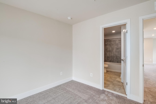 unfurnished bedroom with connected bathroom and light colored carpet