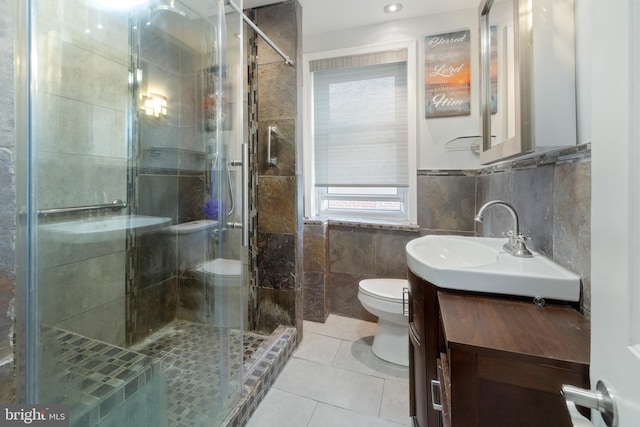 full bath with tile patterned floors, toilet, a stall shower, tile walls, and vanity