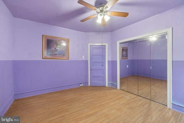 unfurnished bedroom with ceiling fan, a closet, and wood-type flooring