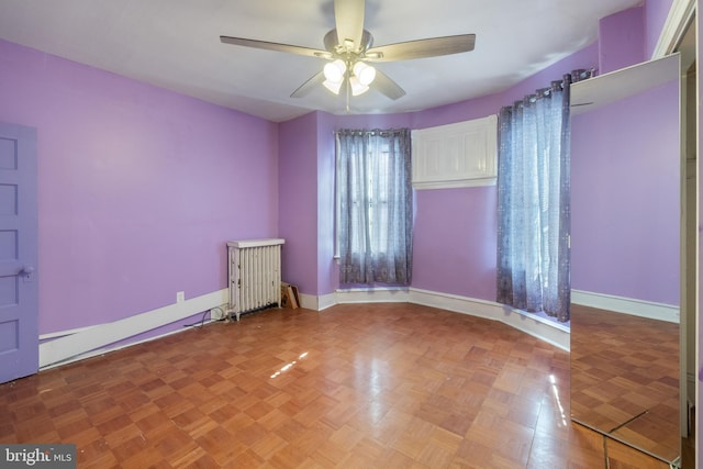 empty room featuring ceiling fan, parquet flooring, and radiator