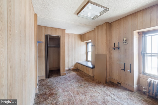 unfurnished bedroom with a textured ceiling, wood walls, and carpet floors