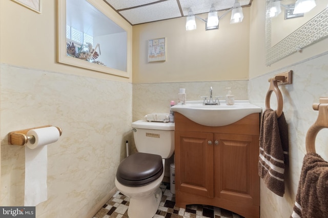 bathroom featuring toilet, vanity, wainscoting, tile walls, and a paneled ceiling