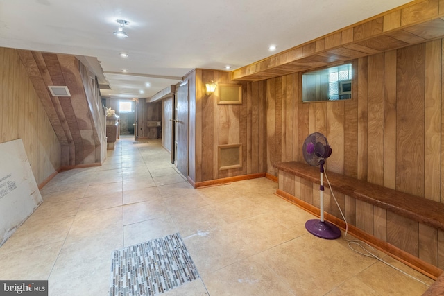 hallway with wooden walls and light tile patterned flooring