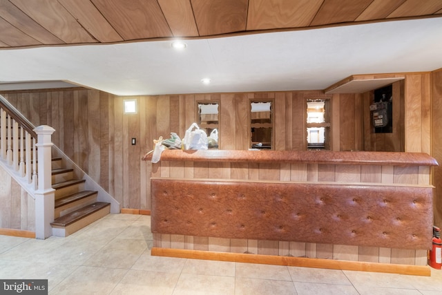 bar with tile patterned floors, wooden walls, and stairway