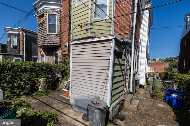 view of property exterior featuring fence and brick siding