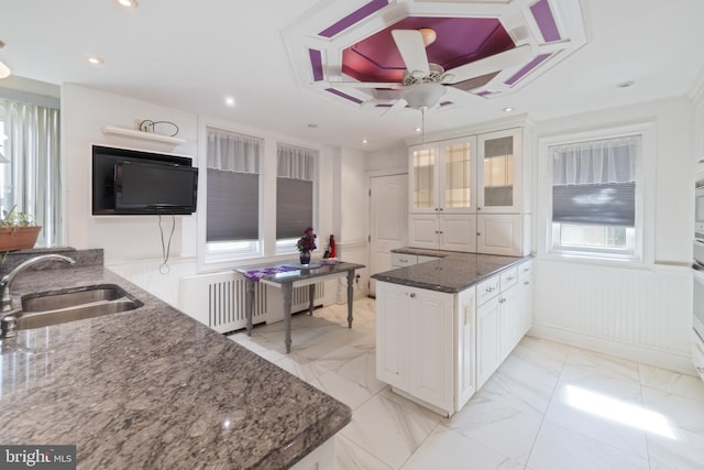 kitchen with a sink, dark stone counters, marble finish floor, and white cabinetry