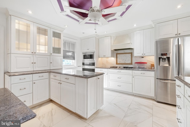 kitchen featuring premium range hood, ceiling fan, decorative backsplash, appliances with stainless steel finishes, and white cabinets