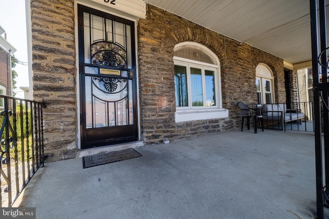 doorway to property featuring covered porch and stone siding