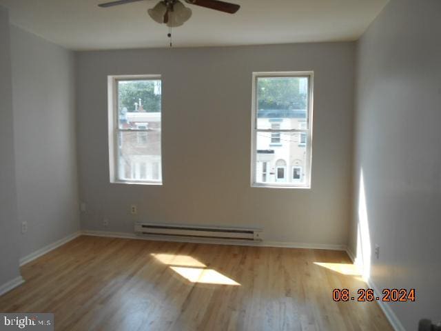 unfurnished room with a wealth of natural light, a baseboard radiator, and light hardwood / wood-style floors