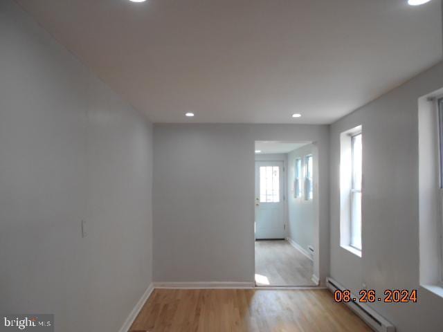 spare room with light wood-type flooring, a baseboard radiator, baseboards, and recessed lighting