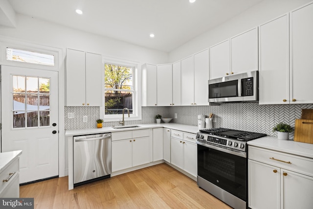 kitchen with white cabinets, appliances with stainless steel finishes, a healthy amount of sunlight, and sink