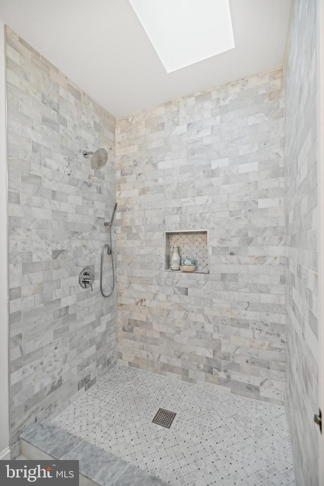 bathroom with tiled shower and a skylight