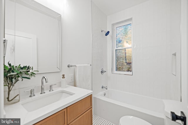 full bathroom featuring tiled shower / bath, vanity, and toilet