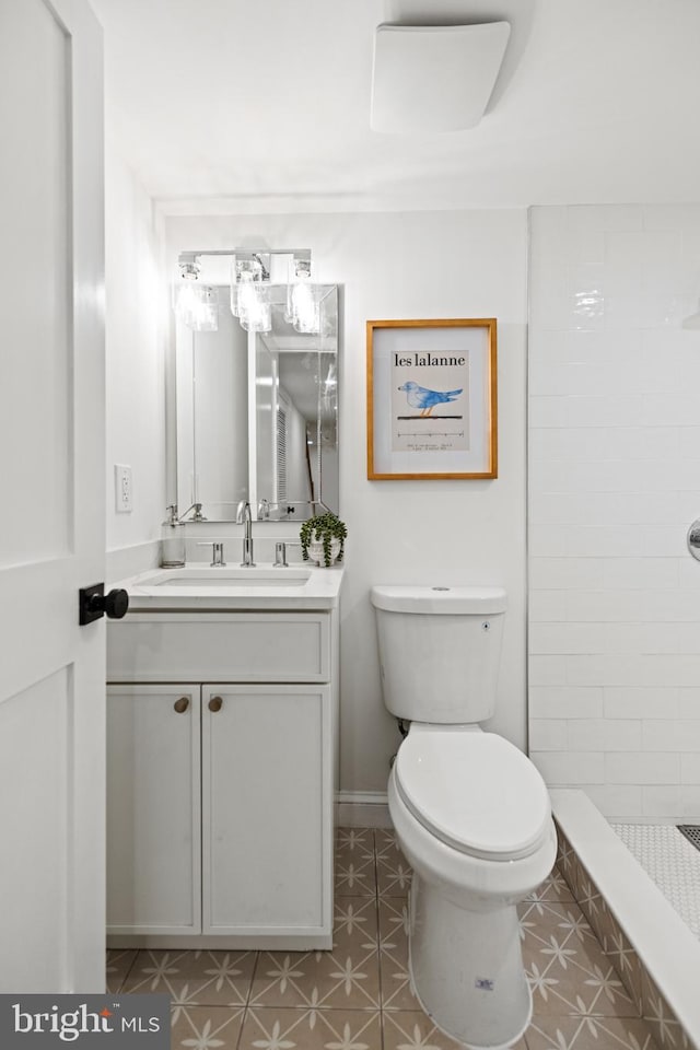 bathroom with a tile shower, vanity, and toilet