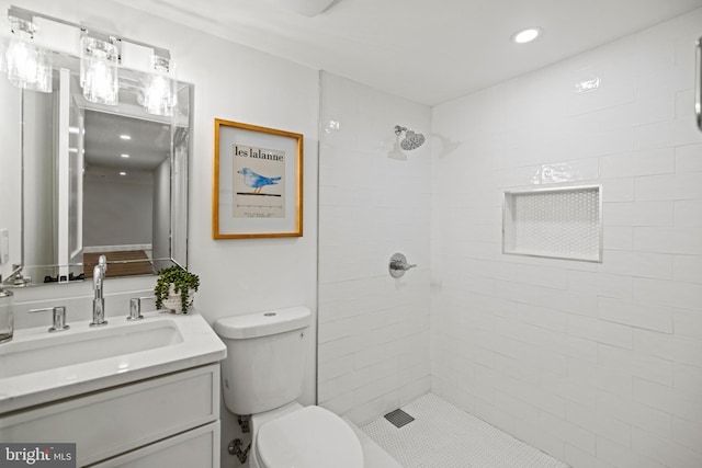 bathroom featuring tiled shower, vanity, and toilet