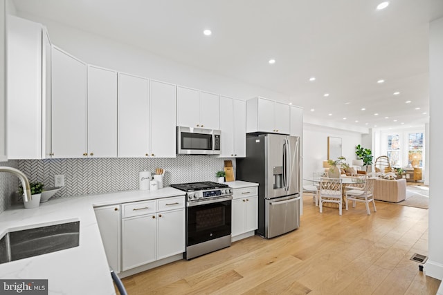 kitchen featuring white cabinets, light hardwood / wood-style floors, sink, and appliances with stainless steel finishes