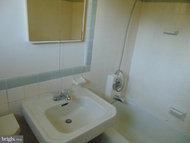 full bathroom featuring tile walls, sink,  shower combination, decorative backsplash, and toilet