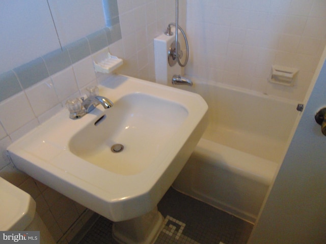 full bathroom featuring a sink, decorative backsplash, and tile walls