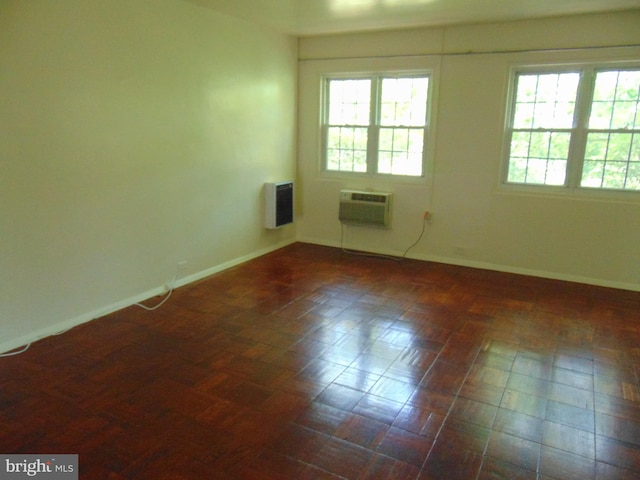 spare room featuring baseboards, a wall mounted air conditioner, and heating unit