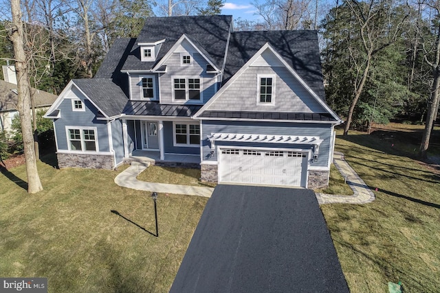 view of front facade featuring a front lawn, stone siding, driveway, and a standing seam roof