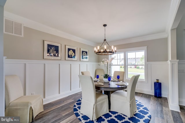 dining space with dark wood-type flooring, a chandelier, visible vents, and ornamental molding