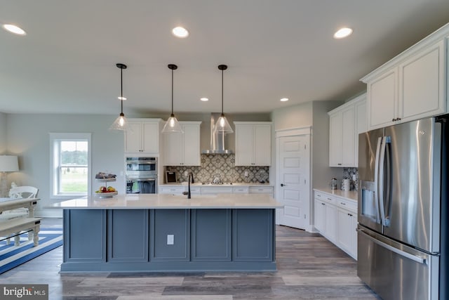 kitchen featuring wall chimney range hood, white cabinets, appliances with stainless steel finishes, and light hardwood / wood-style floors