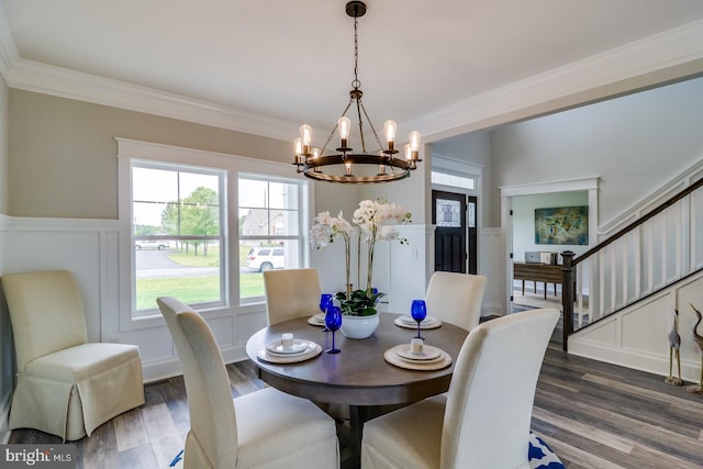 dining room featuring stairs, ornamental molding, a decorative wall, and dark wood-type flooring