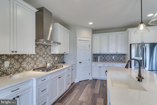 kitchen featuring sink, stainless steel appliances, wall chimney exhaust hood, and decorative backsplash